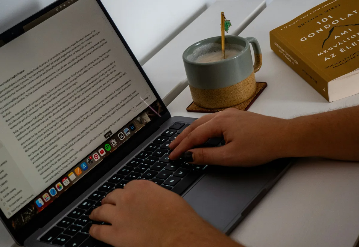 Person typing on laptop with coffee